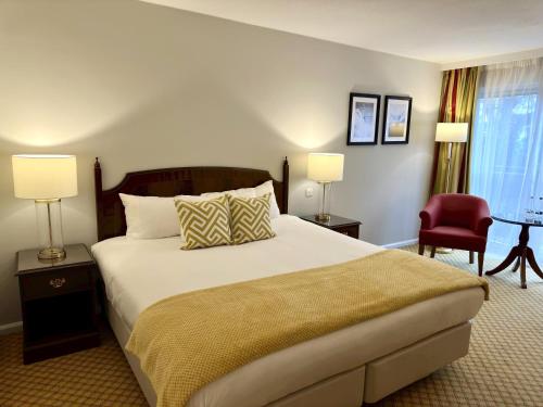 a bedroom with a large bed and a red chair at The Aberdeen Dyce Hotel in Dyce