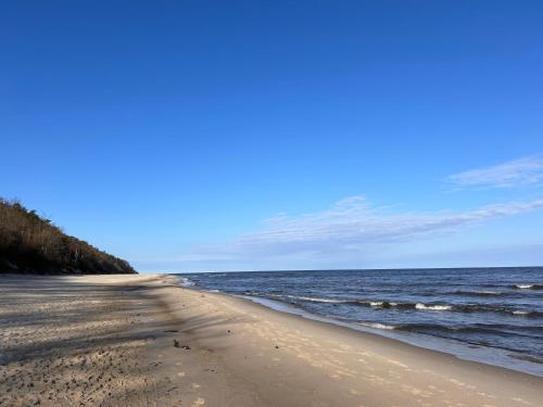 a sandy beach with the ocean in the background at Resort EDEN - domki, pokoje, apartamenty, sauna, jacuzzi in Jastrzębia Góra