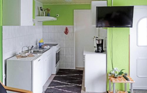 una cocina con armarios blancos y paredes verdes en Cozy Home In Altglobsow With Kitchen, en Altglobsow