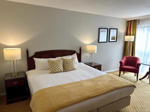 1 dormitorio con 1 cama grande y 1 silla roja en The Aberdeen Dyce Hotel en Dyce