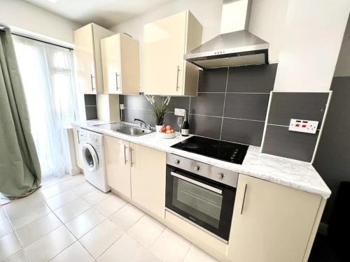 a kitchen with a sink and a stove top oven at Modern 2 bed close to mall with parking & garden in Golders Green