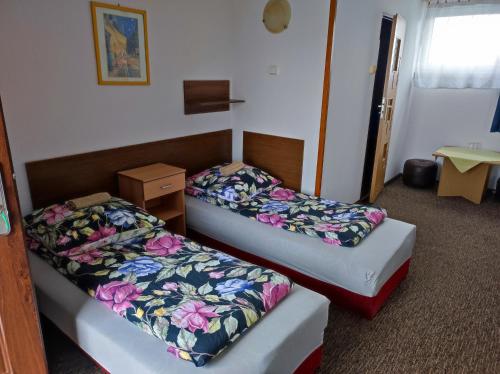 dwa łóżka w pokoju hotelowym z kwiatami w obiekcie Motel Korona w mieście Zamość