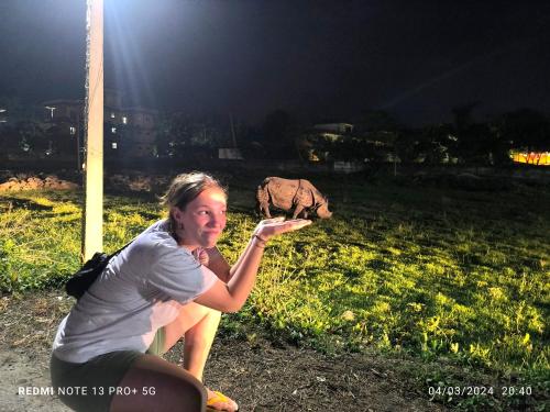 a woman is catching a frisbee with an elephant in the background at Hotel National Park- A peaceful Family home where you can stay Peace and Enjoy and Organize the wildlife Safari in Chitwan