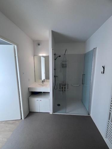 une salle de bain blanche avec une douche et un lavabo dans l'établissement UXCO Le Spot, à La Rochelle