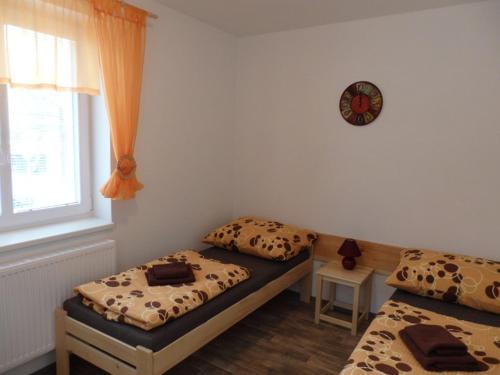 a bedroom with two beds and a clock on the wall at Penzion Terasa při Rybářském a cyklistickém centru in Chlum u Třeboně