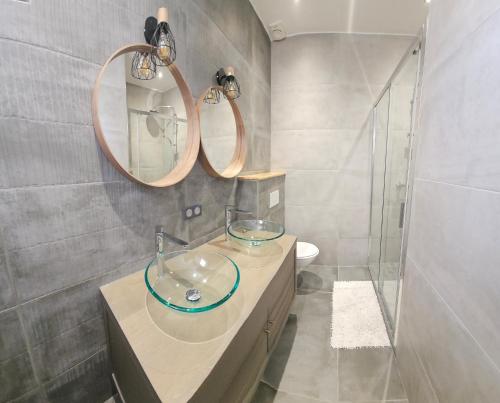 La salle de bains est pourvue d'un lavabo en verre et de deux miroirs. dans l'établissement Les Marronniers, à Lavérune