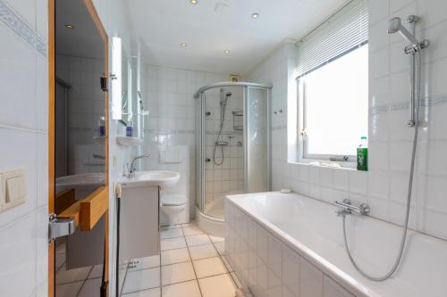 een witte badkamer met een bad en een wastafel bij Vakantiehuis - Middelburgsestraat 61a - Koudekerke 'Villa Querina' in Koudekerke