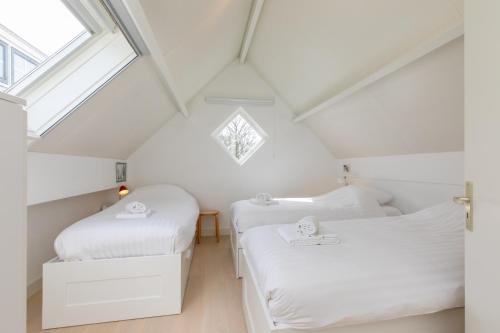 two beds in a attic bedroom with a window at Welcome in - Vakantiehuis - Middelburgsestraat 61a - Koudekerke 'Villa Querina' in Koudekerke
