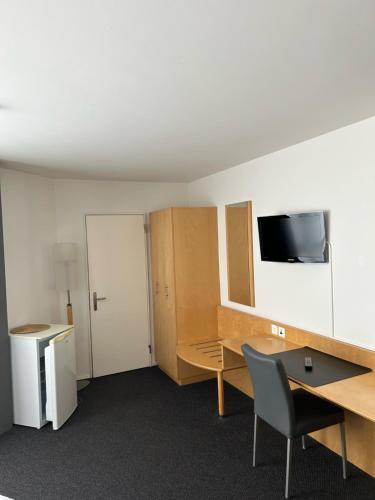 an office with a desk and a tv on the wall at Hotel Domicil in Frauenfeld