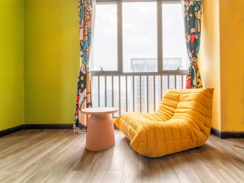 a yellow chair in a room with a window at Wind sleeping Color Hotel - Free car to the Canton Fair-Line7 18Nancun Wanbo STN in Guangzhou