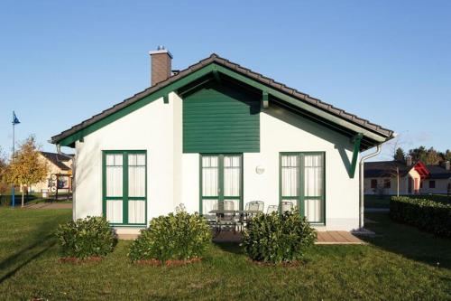 een klein wit huis met een groene luik bij Holiday home in Markkleeberg near a lake in Markkleeberg