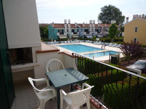 a balcony with a table and chairs and a swimming pool at Le Briccole in Cavallino-Treporti