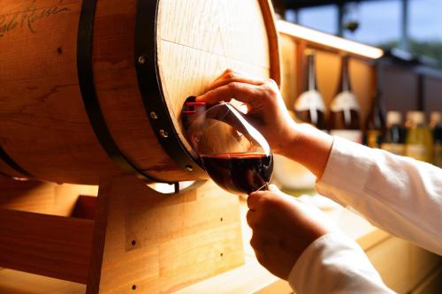 a person pouring a glass of wine in a wine barrel at Spa and Resort Hotel Solage Oita Hiji Beppuwan in Beppu
