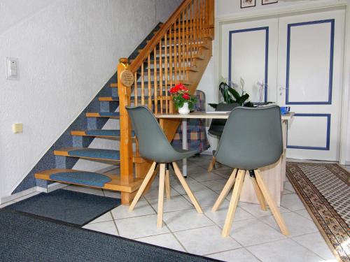 a dining room with a staircase and two chairs at Apartment in Schultenbrook with garden in Metelsdorf