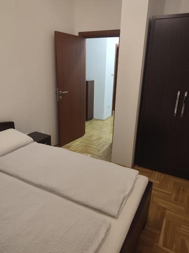 1 dormitorio con 1 cama y puerta que da a un pasillo en Apartman Mia, en Požarevac