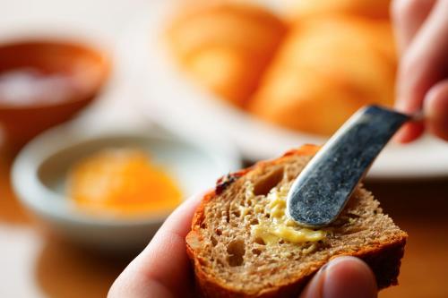 a person holding a piece of bread with a knife at Spa and Resort Hotel Solage Oita Hiji Beppuwan in Beppu