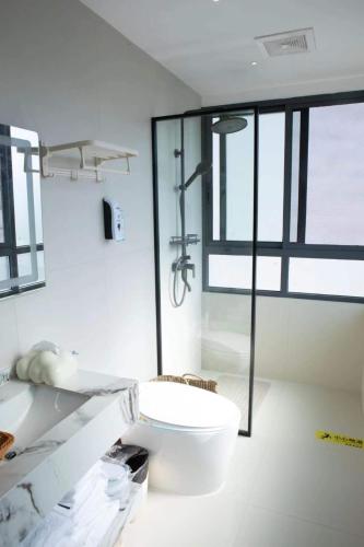 a bathroom with a toilet and a glass shower at Flower Whisperer Homestay Tianmenshan Store free airport and station pick-up in Zhangjiajie