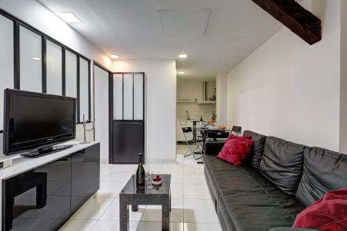 un salon avec un canapé et une télévision à écran plat dans l'établissement 373 Suite Suzanne - Superbe Appartement à Paris, à Paris