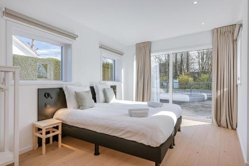 een slaapkamer met een groot bed en een groot raam bij Maison Maurice in Koksijde