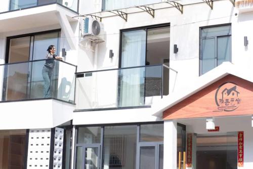 a person standing on the balcony of a building at Flower Whisperer Homestay Tianmenshan Store free airport and station pick-up in Zhangjiajie