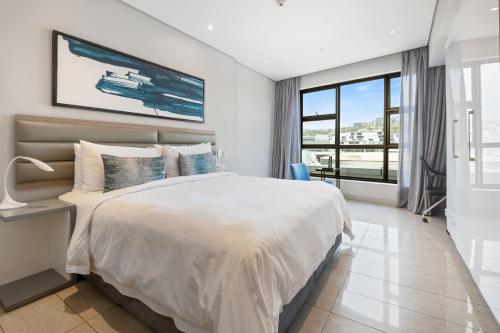 a bedroom with a large bed and a large window at The Capital Pearls Hotel in Durban