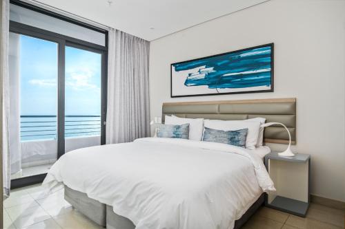 a bedroom with a large bed and a large window at The Capital Pearls Hotel in Durban