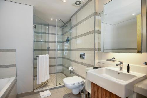 a bathroom with a sink and a toilet and a shower at The Capital Pearls Hotel in Durban