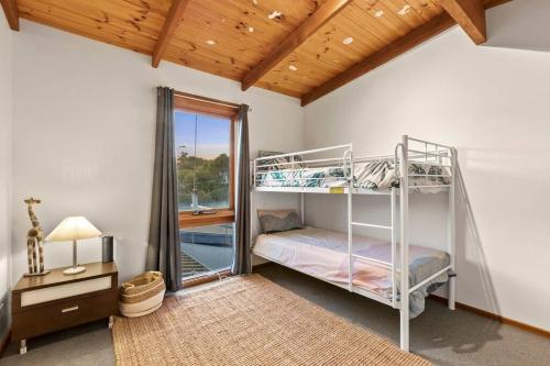 een slaapkamer met 2 stapelbedden en een raam bij Beachside Weekender Retreat with Spa sleeps 11-13 in Ocean Grove