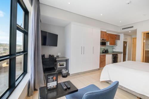 a bedroom with a bed and a desk and a tv at The Capital Pearls Hotel in Durban