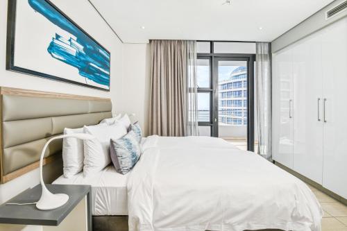 a bedroom with a white bed and a window at The Capital Pearls Hotel in Durban