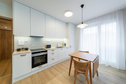 a kitchen with white cabinets and a wooden table at Residence Mozaika in Prague