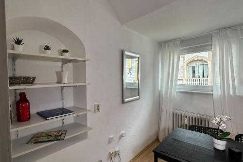 Cette chambre dispose d'étagères blanches, d'une table et d'une fenêtre. dans l'établissement Stadtoase nähe Uni Design Wohnung mit 2 Schlafzimmern & Sauna, à Coblence
