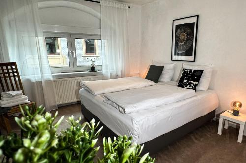 Schlafzimmer mit einem weißen Bett und einem Fenster in der Unterkunft Stadtoase nähe Uni mit Sauna in Koblenz