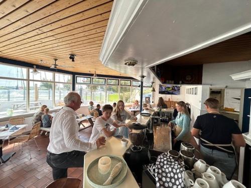 un grupo de personas sentadas en mesas en un restaurante en Minicamping Marina Warns en Molkwerum