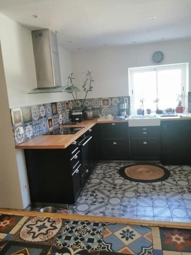 a kitchen with black cabinets and a tile floor at LE HAVRE DE PAIX in Peypin