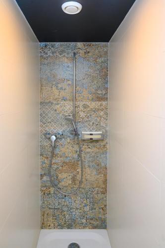 a shower in a bathroom with a tile wall at Appartement-Hotel GH Zum Goldenen Schiff in Enns