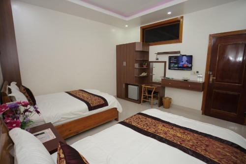 a hotel room with two beds and a flat screen tv at Phong Nha Jasmine Hostel & Roof Top Bar in Phong Nha