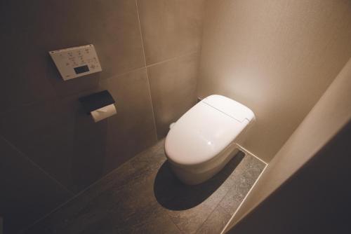 a bathroom with a toilet with a light on the wall at HOTEL MASTAY jingumichi in Kyoto