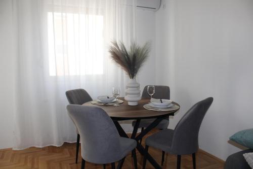 a dining room table with chairs and a vase with a plant at Apartment M in Smederevo