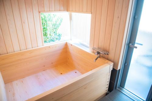 una vasca in legno con finestra in una stanza di 木を楽しむ一棟貸しの宿「ウッドヴィラ 心楽 -SHIGURA-」 a Tamba