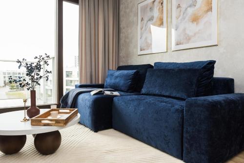 a blue couch in a living room with a table at Sol Marina Resort Wyspa Sobieszewska II - LoftAffair Collection in Wiślinka