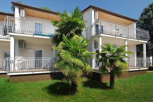 um edifício com duas palmeiras em frente em Ai Pini Medulin Resort em Medulin