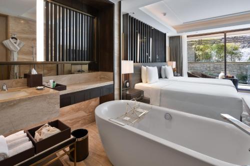 a bathroom with a large tub and a bed and a bath tub at JW Marriott Mussoorie Walnut Grove Resort & Spa in Mussoorie
