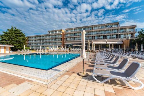 un hôtel avec une piscine et des chaises longues dans l'établissement Arena Hotel Holiday, à Medulin