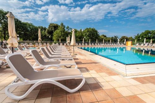 a row of lounge chairs next to a swimming pool at Arena Hotel Holiday in Medulin
