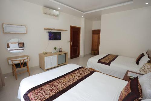 a hotel room with two beds and a mirror at Phong Nha Jasmine Hostel & Roof Top Bar in Phong Nha