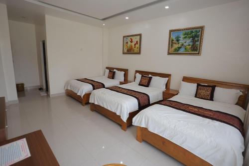 three beds in a room with white walls at Phong Nha Jasmine Hostel & Roof Top Bar in Phong Nha