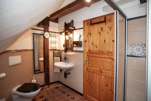 a bathroom with a wooden door and a toilet and a sink at Ferienwohnung Dien Uttied in Grasberg