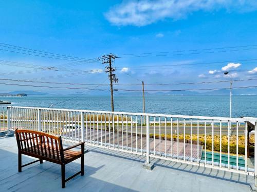 ławka siedząca na balkonie z widokiem na ocean w obiekcie Seaside Villa KAMANO w mieście Aji