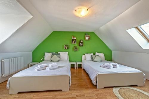 two beds in a attic room with green walls at Maison Rioma - Grande maison à 200m de la plage in Plounéour-Trez